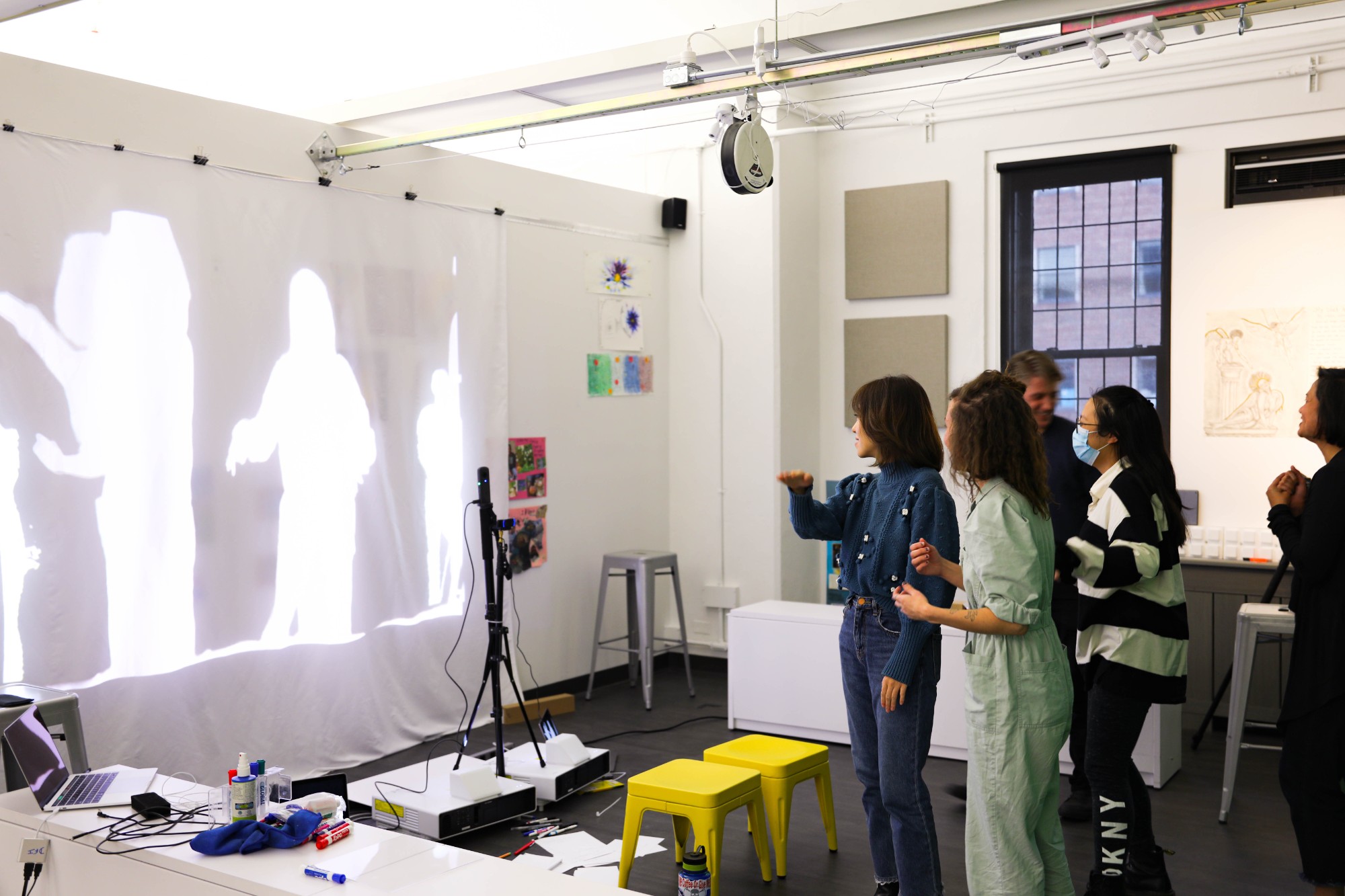 A group of five people at the Gestures Learning exhibit standing near a projection of white silhouettes.